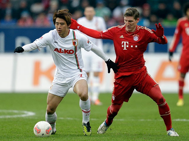 Augsburg's Koo Ja-cheol and Bayern Munich's Bastian Schweinsteiger battle for the ball on December 8, 2012