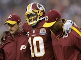 Robert Griffin III of the Washington Redskins is helped off the field on December 9, 2012