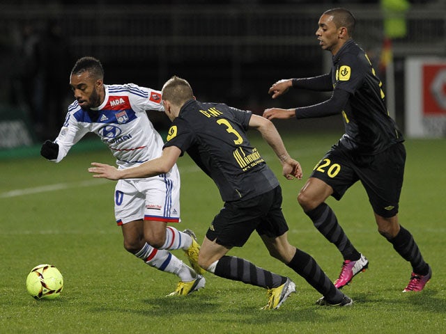 Lyon's Alexandre Lacazette tries to dribble the ball past two Lille players druing their match on February 10, 2013