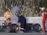 Ferrari development Pedro de la Rosa watches track marshals tend to his car after a fire on February 8, 2013