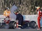 Ferrari development Pedro de la Rosa watches track marshals tend to his car after a fire on February 8, 2013
