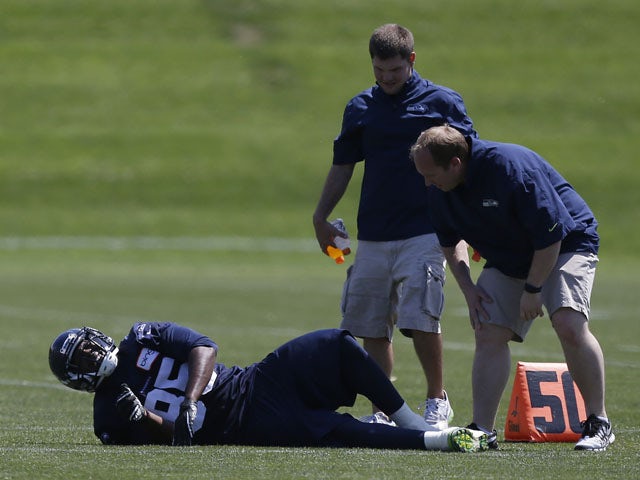Seattle Seahawks team personnel attend to Seahawks' Anthony McCoy during a training session on May 20, 2013