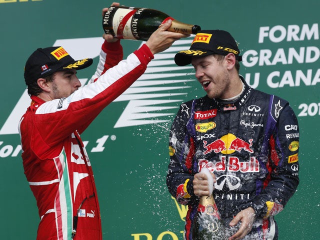 Second place Ferrari driver Fernando Alonso celebrates on the podium spraying champagne to the winner Red Bull driver Sebastian Vettel on June 9, 2013