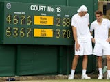 John Isner and Nicolas Mahut stand in front of the scoreboard at Wimbledon.