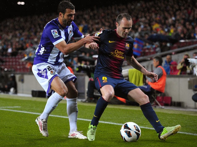Valladolid's Mikel Balenziaga tries to tackle Barcelona's Andres Iniesta during the La Liga clash on May 19, 2013