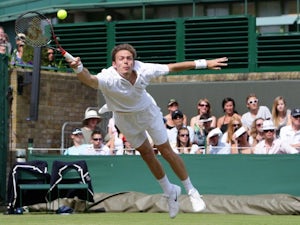 Nicolas Mahut stretches to play a shot in his match against John Isner.