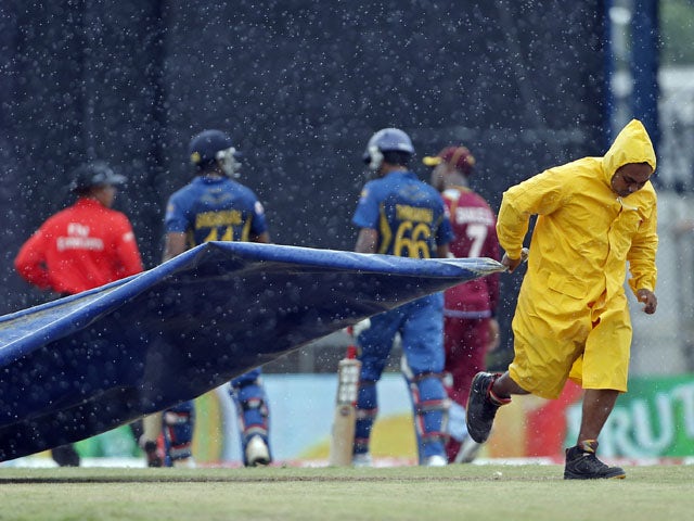 A grounds keeper pulls the tarpaulin to cover the pitch during the match between Sri Lanka and West Indies on July 7, 2013