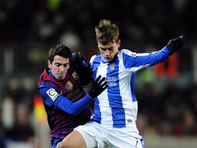 Real Sociedad's Antoine Griezmann challenges for the ball with FC Barcelona's Cuenca during the match on February 4, 2012