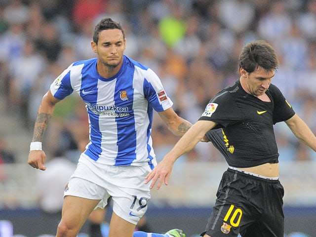 Real Sociedad's Liassine Cadamuro tangles with Barcelona's Lionel Messi during the La Liga match on September 10, 2011