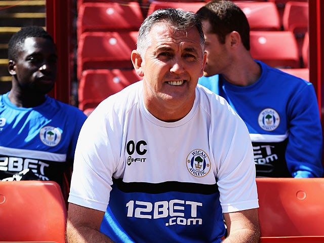 Wigan manager Owen Coyle smiles in the dugout before kick off against Barnsley on August 3, 2013