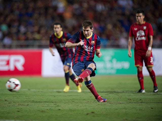 FC Barcelona's Lionel Messi takes a penalty shot against Thailand during their exhibition match with Thailand's national football team on August 6, 2013