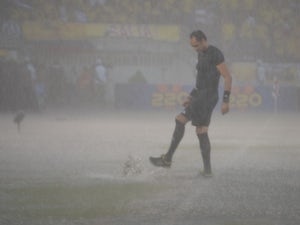 One of the referees inspects the field during a heavy downpour before the start of the Brazil 2014 FIFA World Cup South American qualifier match between Colombia and Ecuador, in Barranquilla, Colombia, on September 6, 2013