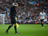 Referee's assistant David Bryan clutches his shirt after he was hit by a missile from the crowd during the Barclays Premier League match between Aston Villa and Tottenham Hotspur at Villa Park on October 20, 2013 