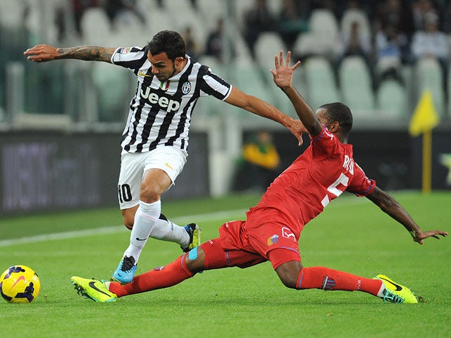 Juventus' Carlos Tevez and Catania's German Rolin battle for the ball on October 30, 2013