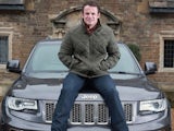 Austin Healey poses on a Jeep after becoming an ambassador for the car company