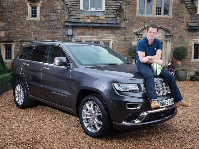 Austin Healey poses on a Jeep after becoming an ambassador for the car company