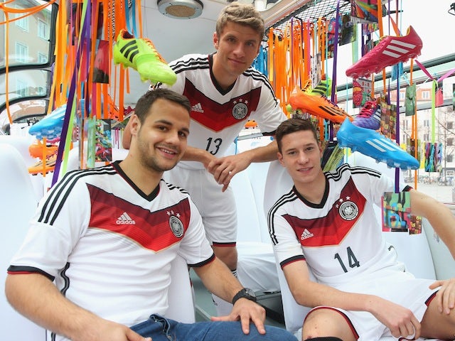 Playmakers Thomas Muller (C) and Julian Draxler (R) help unveil the Germany World Cup kit in Munich on November 12, 2013