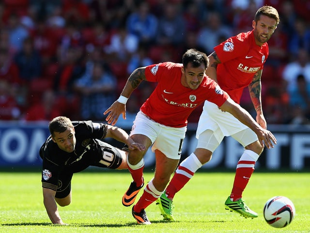 Shaun Maloney of Wigan Athletic and Chris Dagnall of Barnsley challenge for the ball during the Sky Bet Championship match between Barnsley and Wigan Athletic at Oakwell on August 03, 2013