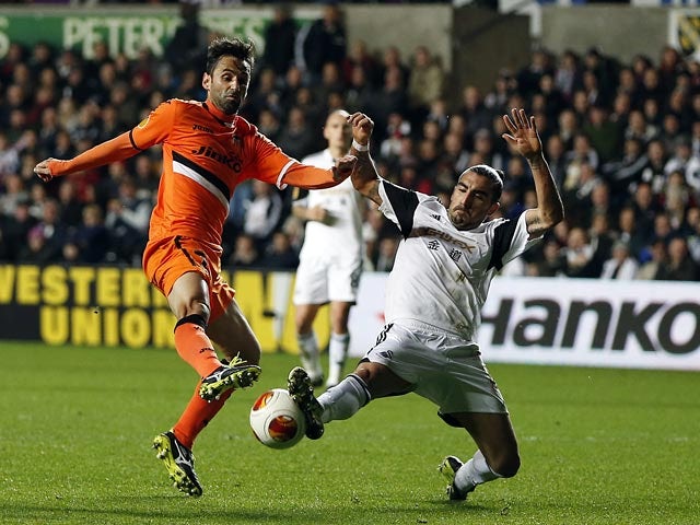 Swansea's Chico Flores and Valencia's Jonas battle for the ball during their Europa League group match on November 28, 2013
