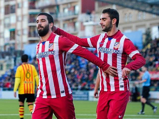 Atletico Madrid's Arda Turan celebrates with teammate Adrian Lopez after scoring his team's second goal against Sant Andreu during their Copa del Rey on December 7, 2013