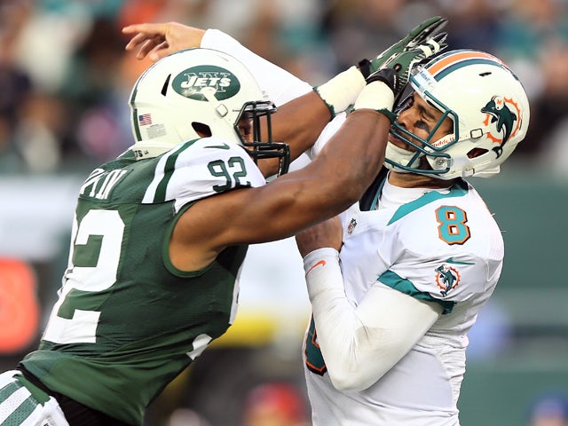 Marcus Dowtin #92 of the New York Jets is called for roughing the passer as he collides with Matt Moore #8 of the Miami Dolphins on October 28, 2012