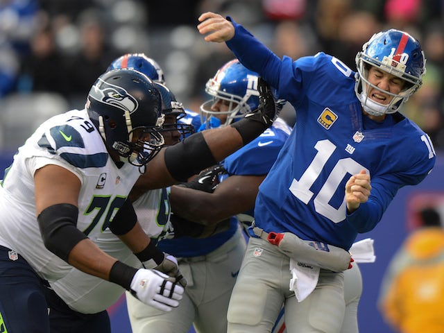 Quarterback Eli Manning of the New York Giants is hit as he throws a pass in the 1st half against the Seattle Seahawks at MetLife Stadium on December 15, 2013