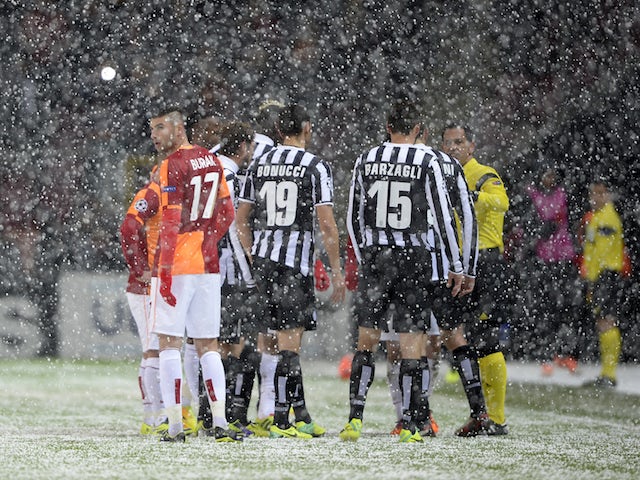 Galatasaray's and Juventus' players speak with referee Pedro Proenca after a heavy snow fall halted their UEFA Champions League group B football match at the TT Arena Stadium on December 10, 2013