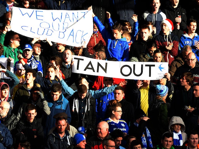 Cardiff City supporters hold banners opposing their club's Malaysian owner Vincent Tan during the English Premier League football match against Liverpool on December 21, 2013