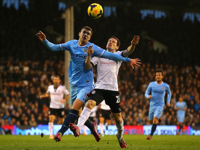 Edin Dzeko of Manchester City and Sascha Riether of Fulham battle for the ball during the Barclays Premier League match on December 21, 2013
