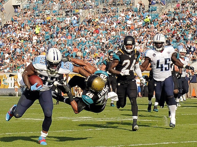 Shonn Greene of the Tennessee Titans runs through Josh Evans of the Jacksonville Jaguars during a game at EverBank Field on December 22, 2013
