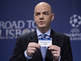 UEFA general secretary Gianni Infantino holds up the name of Greek club Olympiacos during the draw for the last 16 of the UEFA Champions league tournament at the UEFA headquarters in Nyon on December 16, 2013