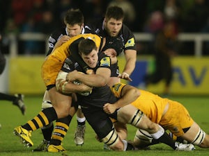 Mark Wilson of Newcastle is tackled by Carlo Festuccia and Sam Jones during the Aviva Premiership match between Newcastle Falcons and London Wasps at Kingston Park on December 27, 2013 