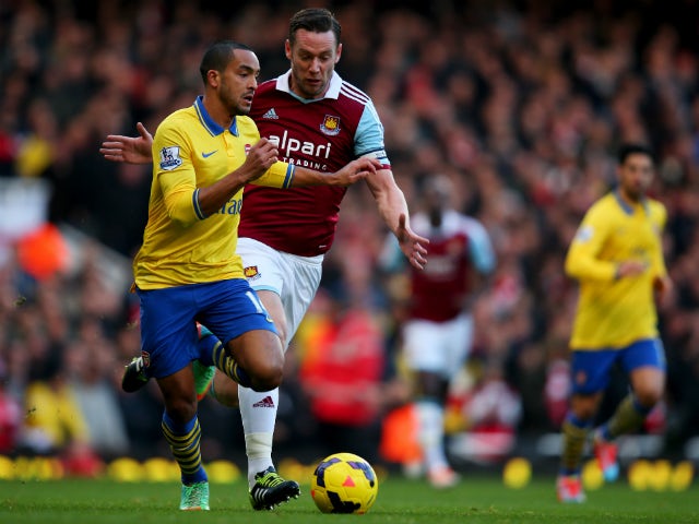 Theo Walcott of Arsenal is chased by Kevin Nolan of West Ham United during the Barclays Premier League match between West Ham United and Arsenal at Boleyn Ground on December 26, 2013