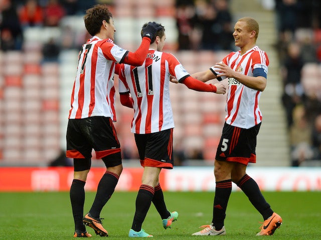 Adam Johnson of Sunderland celebrates with teammates Ji Dong-Won and Wes Brown after scoring the opening goal from a free kick during the game against Carlisle on January 5, 2014