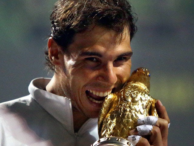 Rafael Nadal bites the trophy after beating Gael Monfils in the Qatar Open final on January 4, 2013