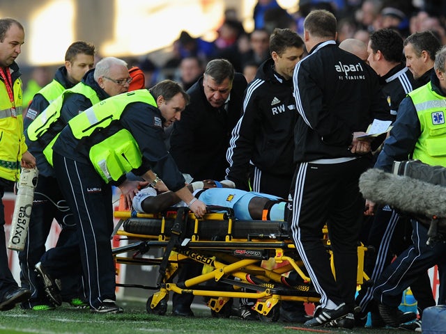 West Ham manager Sam Allardyce checks on the wellbeing of player Guy Demel who is stretchered off during the Barclays Premier League match between Cardiff City and West Ham United at Cardiff City Stadium on January 11, 2014