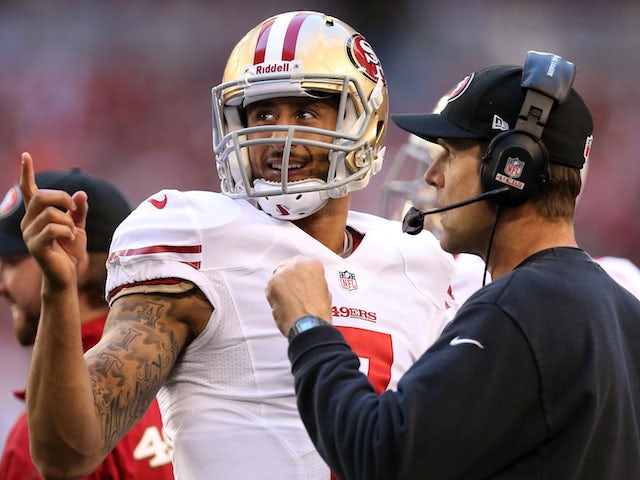Colin Kaepernick of the San Francisco 49ers talks with head coach Jim Harbaugh on the sidelines against the Arizona Cardinals on January 5, 2014