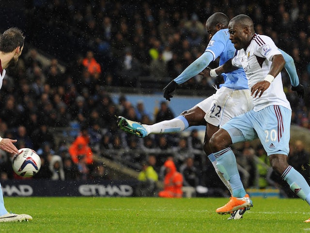 Manchester City's Ivorian midfielder Yaya Toure (2R) scores his team's third goal as West Ham United's Ivorian defender Guy Demel (R) defends during the English League Cup semi-final on January 8, 2014