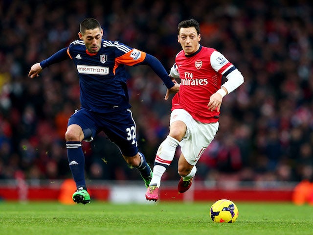 Mesut Ozil of Arsenal holds off Clint Dempsey of Fulham during the Barclays Premier League match between Arsenal and Fulham at Emirates Stadium on January 18, 2014 