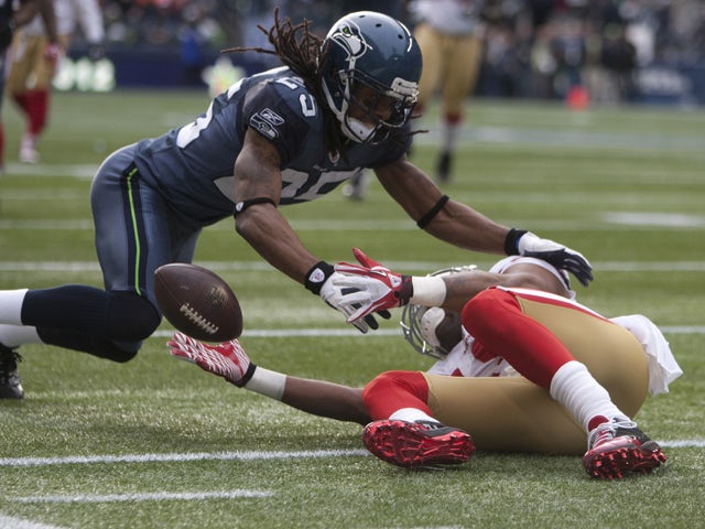 Wide receiver Michael Crabtree #15 of the San Francisco 49ers reaches for the ball as Richard Sherman #25 of the Seattle Seahawks dives in at CenturyLink Field December 24, 2011
