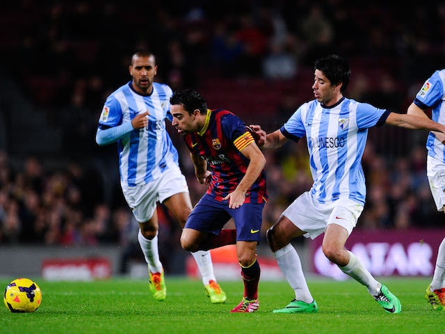 Xavi Hernandez of FC Barcelona duels for the ball with Pablo Perez of Malaga CF during the La Liga match between FC Barcelona and Malaga CF at Camp Nou on January 26, 2014