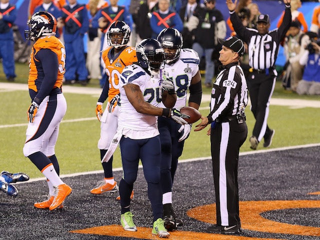 Running back Marshawn Lynch #24 of the Seattle Seahawks hands ball over after scoring a one yard touchdown against the Denver Broncos on February 2, 2014