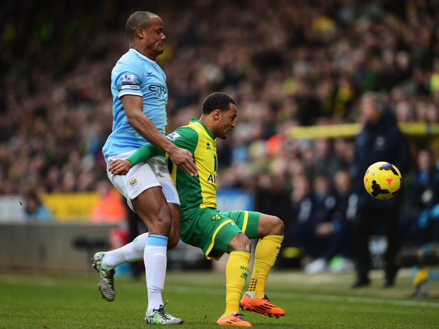 Nathan Redmond of Norwich City holds off the challenge of Vincent Kompany of Manchester City during the Barclays Premier League match between Norwich City and Manchester City at Carrow Road on February 8, 2014