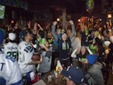 Seattle Seahawks fans including Lynnsey Sturgeon (C) react while watching their team play the Denver Broncos in the Super Bowl at 95 Slide, a sports bar in Seattle on February 2, 2014