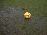 A ball sits on a waterlogged pitch