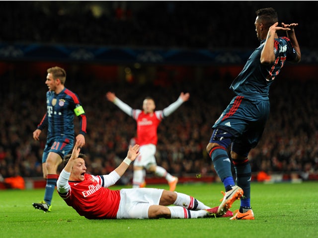 Jerome Boateng of Bayern Muenchen brings down Mesut Ozil of Arsenal in the area for a penalty during the UEFA Champions League Round of 16 first leg match between Arsenal and FC Bayern Muenchen at Emirates Stadium on February 19, 2014