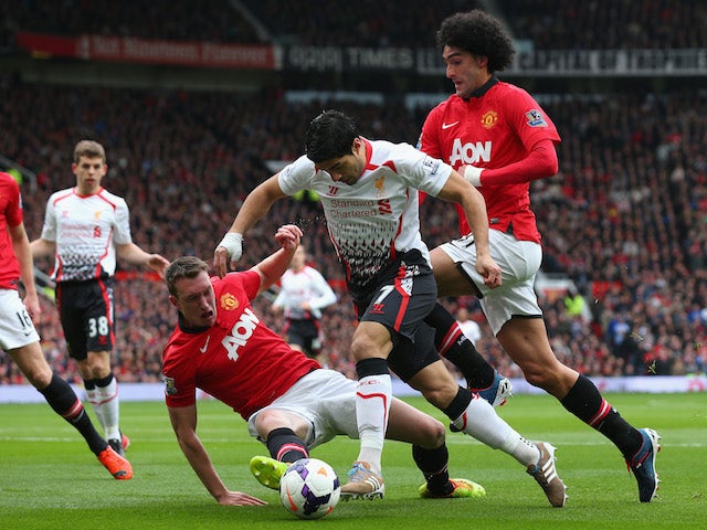 Luis Suarez is tackled by Phil Jones and Maroune Fellaini during the Barclays Premier League game between Manchester United and Liverpool at Old Trafford on March 16, 2014