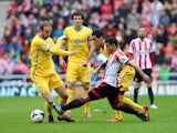 Liam Bridcutt of Sunderland clears the ball ahead of Thomas Ince of Crystal Palace during the Barclays Premier League match between Sunderland and Crystal Palace at The Stadium of Light on March 15, 2014