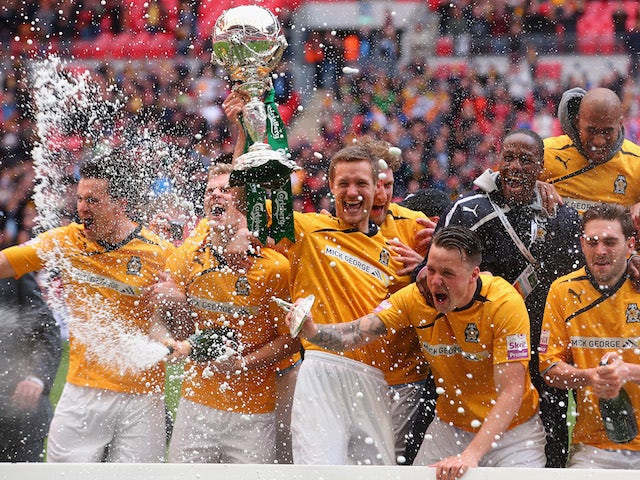 Ian Miller of Cambridge United lifts the trophy as his team celebrate during the FA Carlsberg Trophy Final 2014 at Wembley Stadium on March 23, 2014 