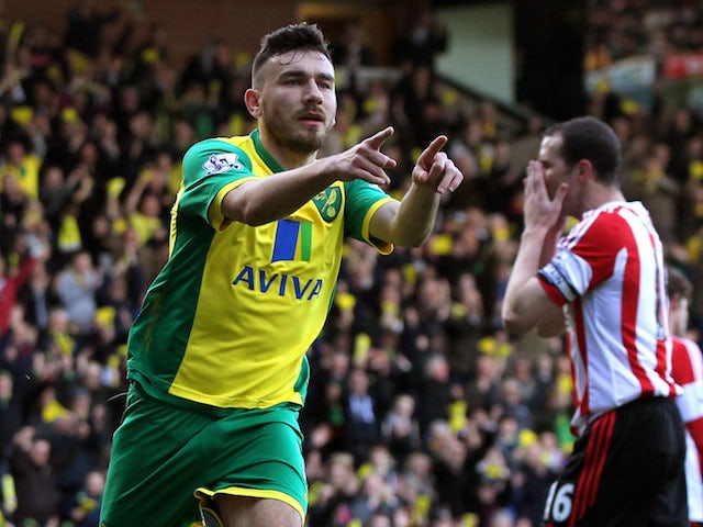Robert Snodgrass of Norwich City celebrates scoring the opening goal as a dejected John O'Shea of Sunderland reacts during the Barclays Premier League match on March 22, 2014